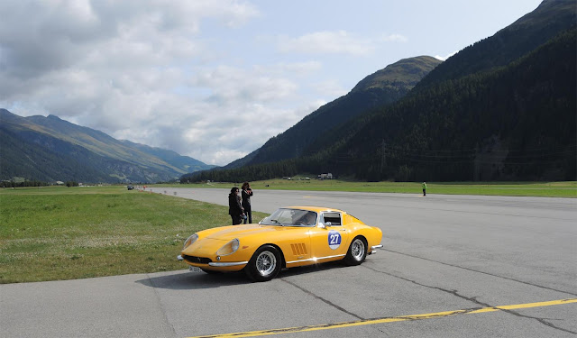   Gelber Ferrari 275 GTB bei  Fahrprüfung auf Flugbahn des Airport Engadin, Berge und Wiesen im Hintergrund