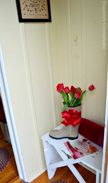 Tulips in a rain boot on bench in mudroom