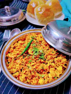 Serving egg bhurji in a serving bowl, pav in background