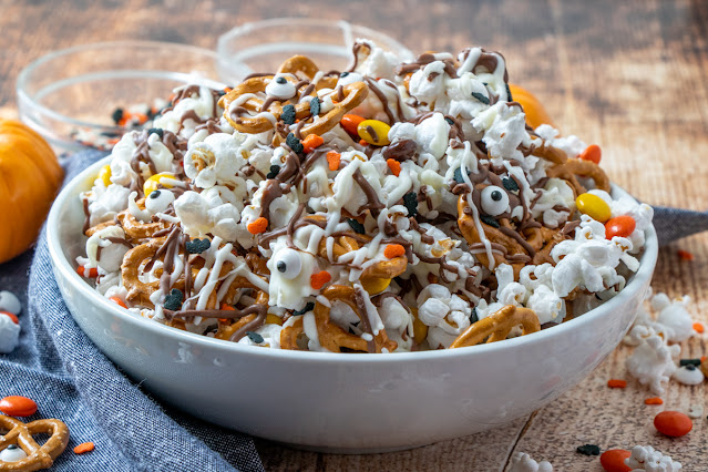 White bowl filled with chocolate covered popcorn and candy