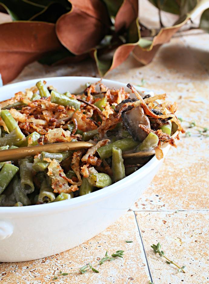 Recipe for a green bean casserole made with mushrooms, caramelized onions and a creamy béchamel sauce, topped with homemade crispy onions.