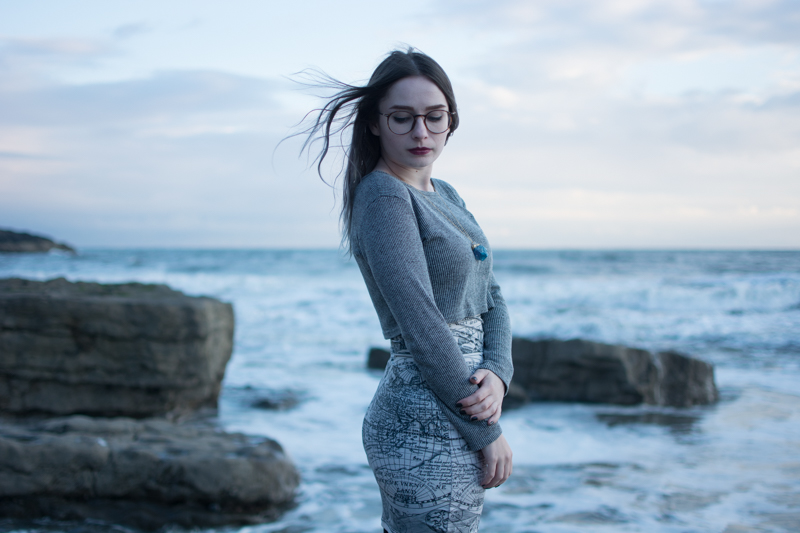 portrait of a girl on the beach long sleeve crop top black milk ancient maps bodycon dress big hipster glasses crystal necklace