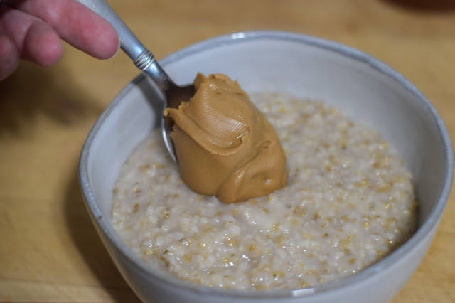 Peanut butter being added to the bowl of steel cut oats.