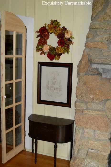 Unpainted French Door in living room next to small table and stone fireplace