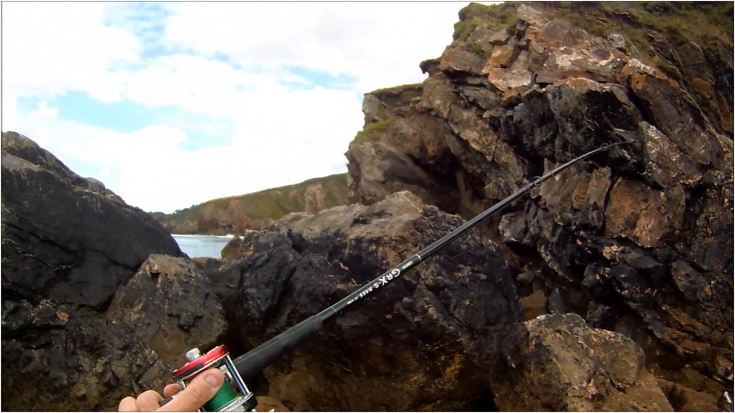 Cornish Shore and Kayak Fisherman Bait Fishing for Sea Bass from the Rocks