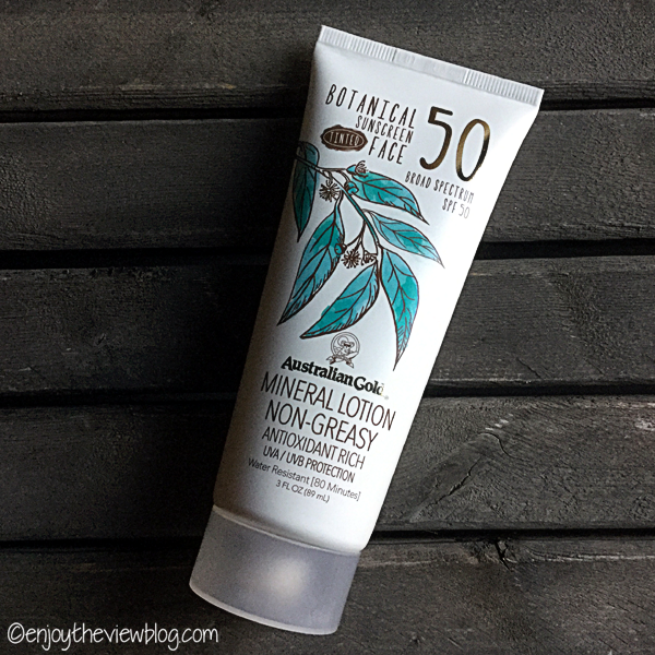 A tube of Australian Gold Botanical Tinted Facial Lotion SPF 50 lying on a wooden table