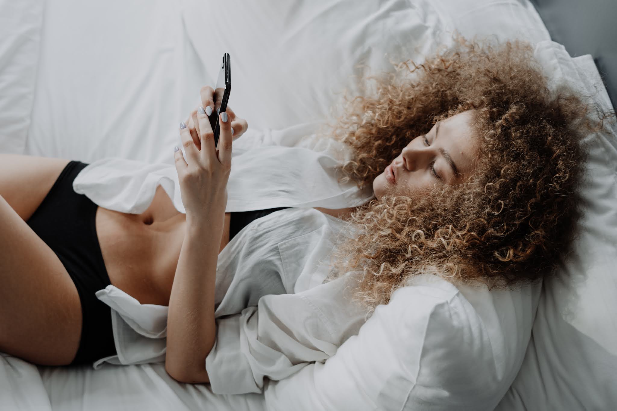 Woman scrolling on her phone in bed