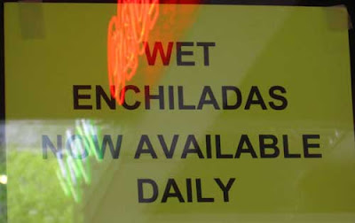 Yellow handmade sign reading WET ENCHILADAS NOW AVAILABLE DAILY