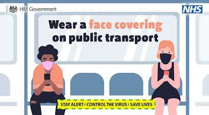 Face Coverings on Public Transport UK Government advert shows two people sitting apart wearing face coverings