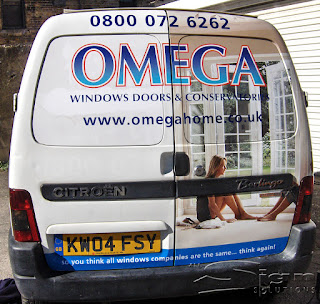 Omega windows doors & conservatories rear of van. One side of the door has two women conversing sitting on the floor of the newly built and finished conservatory. The bottom of the van has the tag line 'so you think all window companies are the same... think again!'