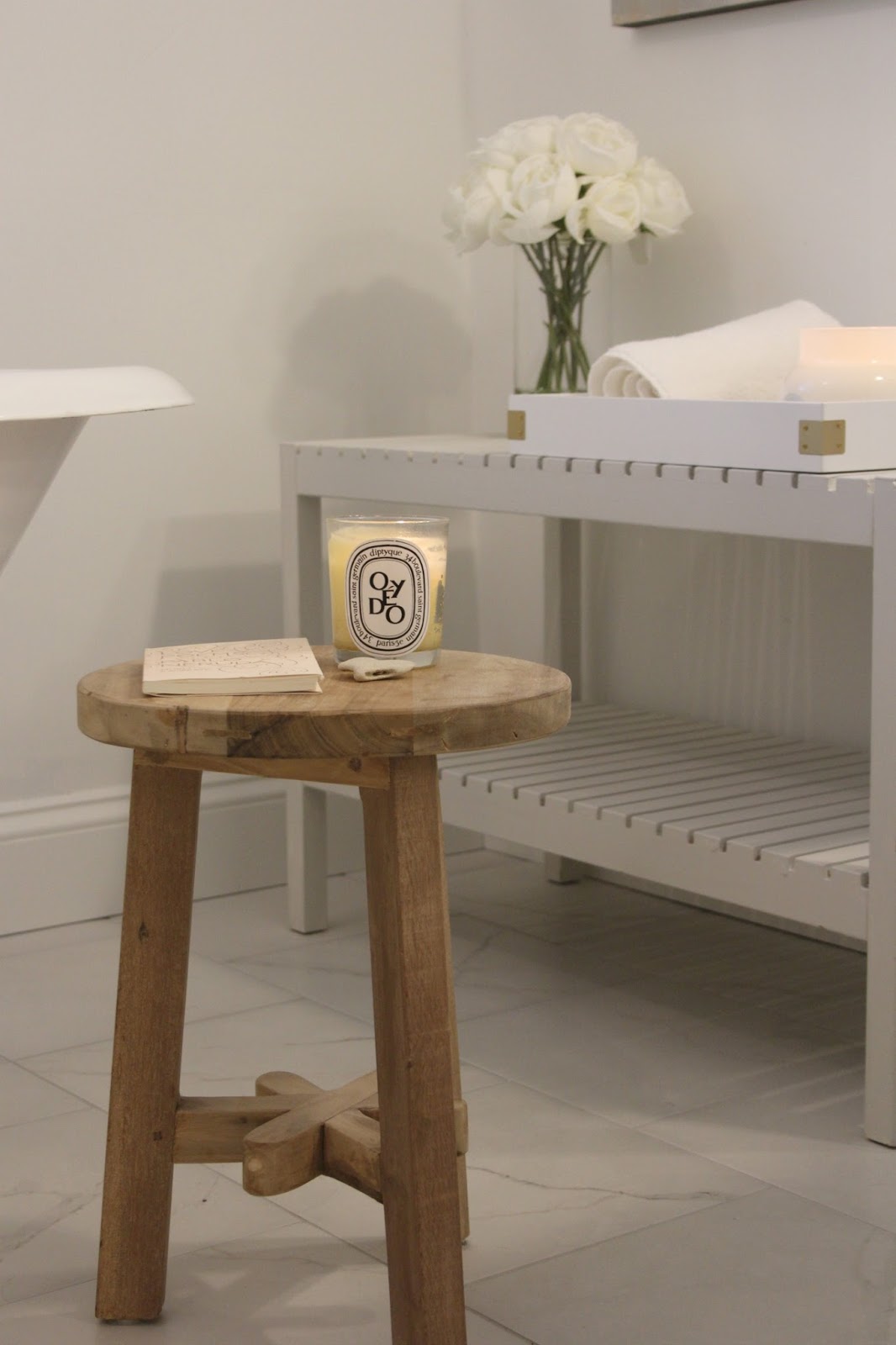 Diptyque candle (Oyedo) on a teakstool near the soaking tub in the bath (BM OC-151) - Hello Lovely Studio.