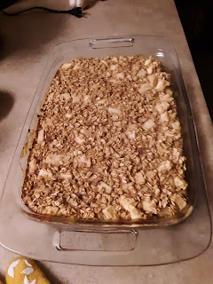 a glass nine-by-thirteen pan containing a golden-brown breakfast oatmeal casserole.  Apple cubes are visible sticking out of oats.
