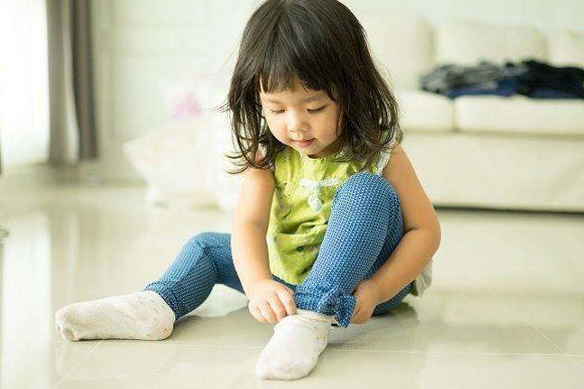 Дети одеты плохо. Ребенок одевается. Маленькая девочка в носочках. Девочка надевает носки. Одеваться.