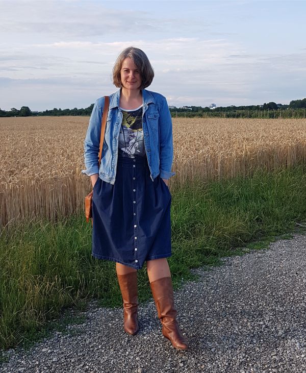 Kühler Sommerabend mit Midijeansrock in dunkelblauer Waschung, mit Knopfleiste, auf der Hüfte getragen und mit heller Jeansjacke kombiniert.