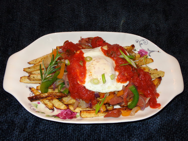 PORTIONS: 1 INGREDIENTS 2 large washed potatoes with skin cut in batons  1 tbsp. rosemary leaves, chopped 1 hot dog, sliced 1 garlic clove, minced ½ red onion, cut in Julienne ¼ orange pepper, cut in Julienne ¼ green pepper, cut in Julienne ½ tsp. fresh hot pepper 1 egg ½ cup tomato sauce 1 tbsp. sliced scallions Salt and pepper to taste Garlic powder METHOD Dry the potatoes with paper towel and place them in a baking sheet pan. Season the potatoes with rosemary, salt, pepper, garlic powder and olive oil. Mix well the potatoes and separate them on the baking pan. Turn your broiler oven on and cook the potatoes until are crispy and golden brown. Meanwhile, heat a frying pan with bit of olive oil and sauté garlic and onions together. Add peppers, sliced hot dog, hot pepper, season it with salt, pepper and sauté for 1 minute. Heat up the tomato sauce. Once potatoes are cooked, arrange in a serving dish. Place the peppers with hot dog on top. Cover with a fry egg and tomato sauce. Sprinkle the top with scallions.
