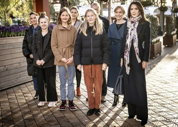 Crown Princess Mary wore a trench coat by Fonnesbech, and high-heel boots by Pura Lopez, and gold earrings by Marianne Dulong. Prada Saffiano bag