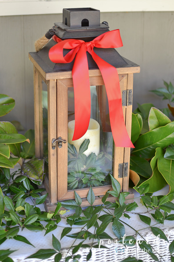 wooden lantern with fresh greenery and red satin ribbon