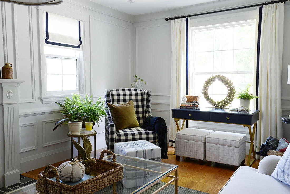fall living room, fall decor ideas, moulding on walls, roman blind with banding, buffalo plaid arm chair, cube ottoman, ottoman with storage, brass wreath
