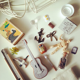 Selection of pieces for use in a one-twelfth scale dollshouse scene, including a glittery guitar, a jar of miniature shells and some metal pieces.