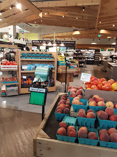 image of brightly-lit produce displaces with peaches in the foreground and tomatoes in the mid-distance