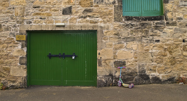 green warehouse door and child's scooter at the Daftmill Distillery