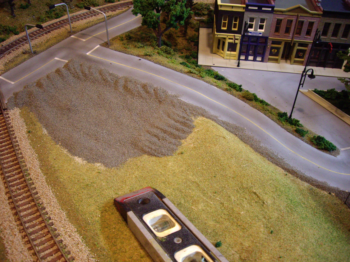 Sifted dirt being added to the edges of plaster roads and a parking lot