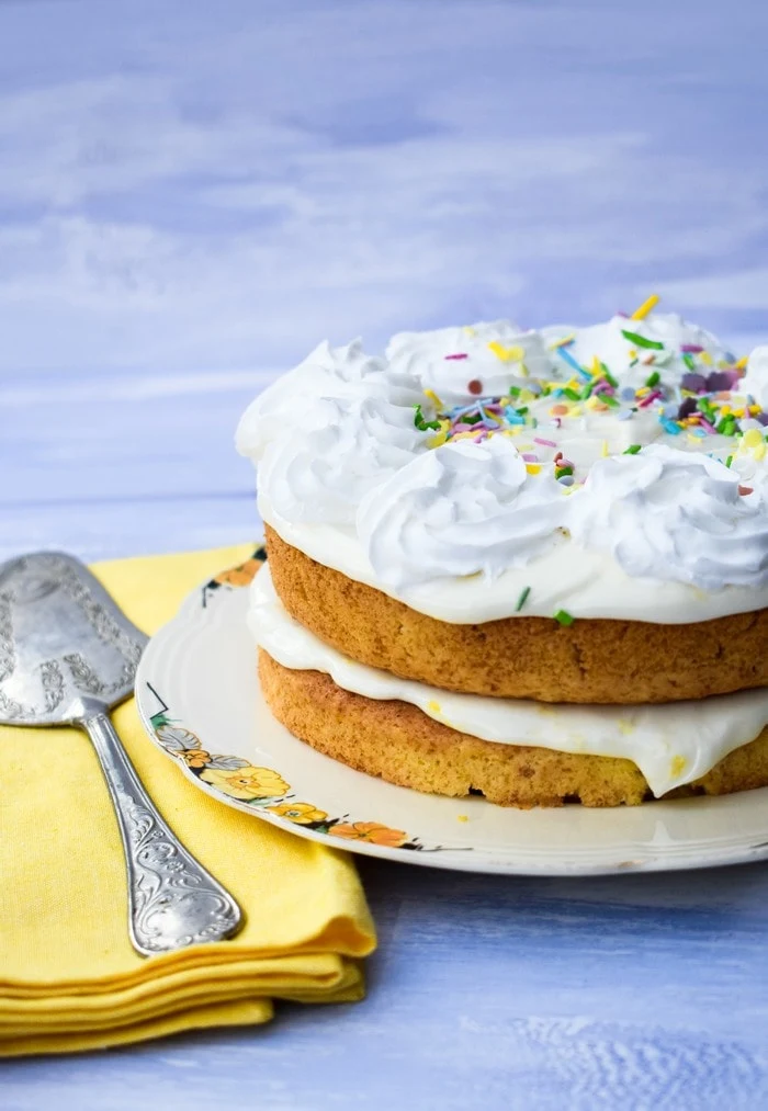 Quick Vegan Lemonade Cake on a cream plate with yellow napkin and cake slice