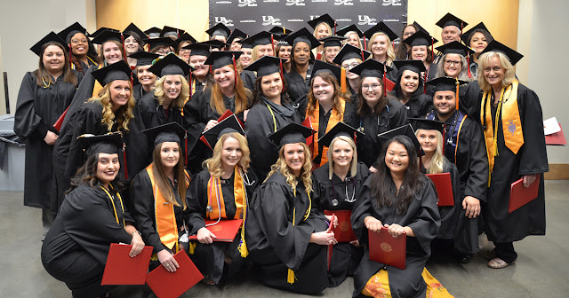 A gathering of graduates in front of a UACCM banner