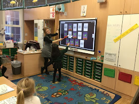 Opettaja ja vuorossa oleva oppilas pelaavat muistipeliä Smart-taululla luokan edessä.