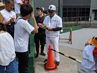 試合前にサインに応じる村田コーチ