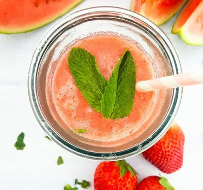 overview of Watermelon & Strawberry Iced Smoothie in a glass topped with a fresh mint leaf