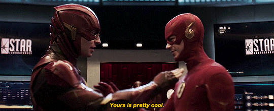 Gif: o personagem Barry Allen, interpretado por Ezra Miller encostando no uniforme do personagem Barry Allen, interpretado por Grant Austin na série da CW.