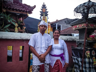 Happy Couple Using Traditional Balinese Clothes In Front Of Small Balinese Hindu Temple In The House
