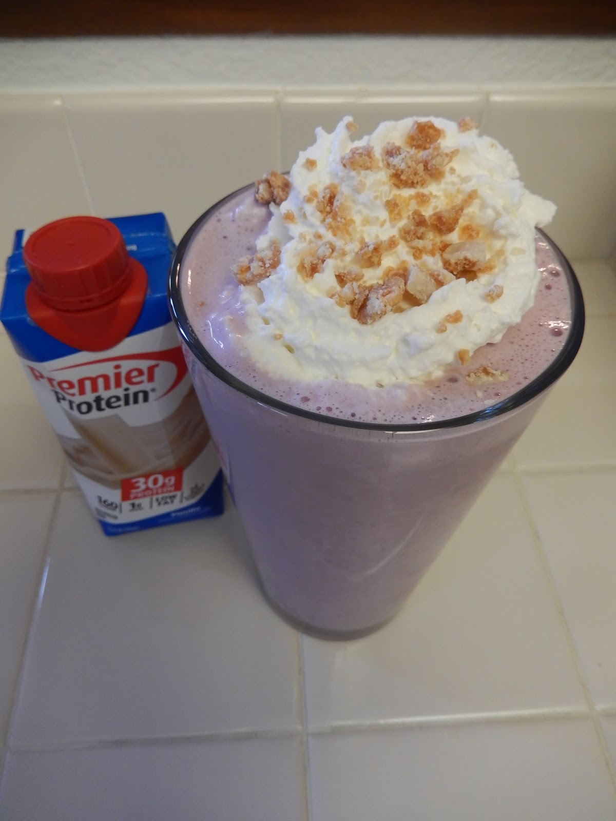 A cherry colored smoothie topped with crumbs, cherries and Grenola