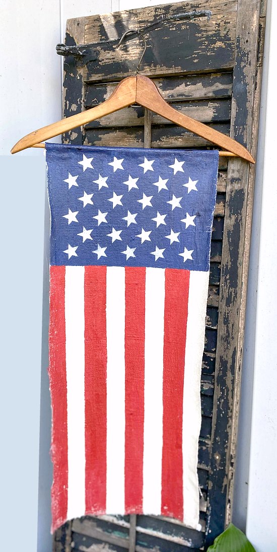 American Flag painted on painter's cloth in front of a black chippy shutter