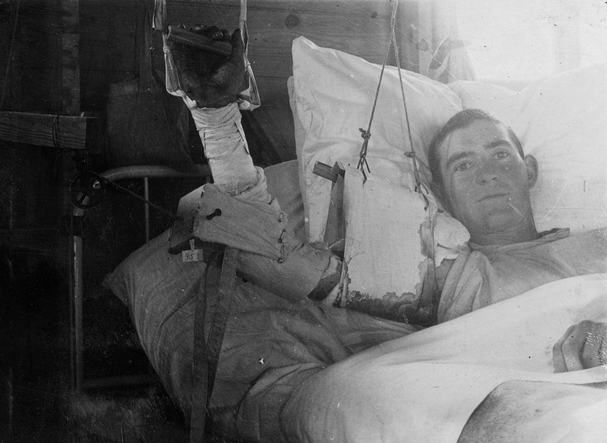 A wounded man recovers in a hospital bed.