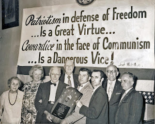 Yazar Benjamin H. Freedman "Vatanseverlik özgürlüğü savunmaktır, büyük bir erdemdir. Korkaklık ise komünizmin yüzüdür, tehlikelidir." yazılı pankartın önünde ödül alıyor, 1972