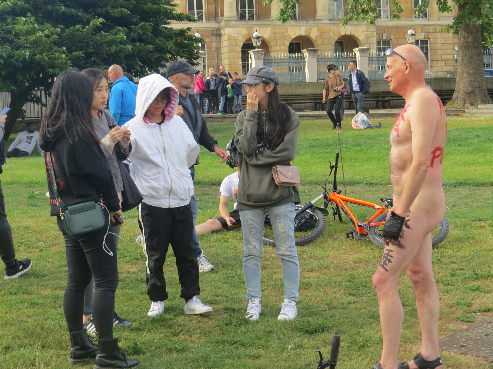 Asian girls inspecting a Nude Man in London Parade. 