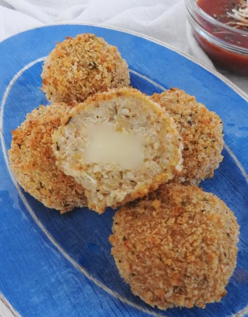 arancini on blue plate with side of sauce