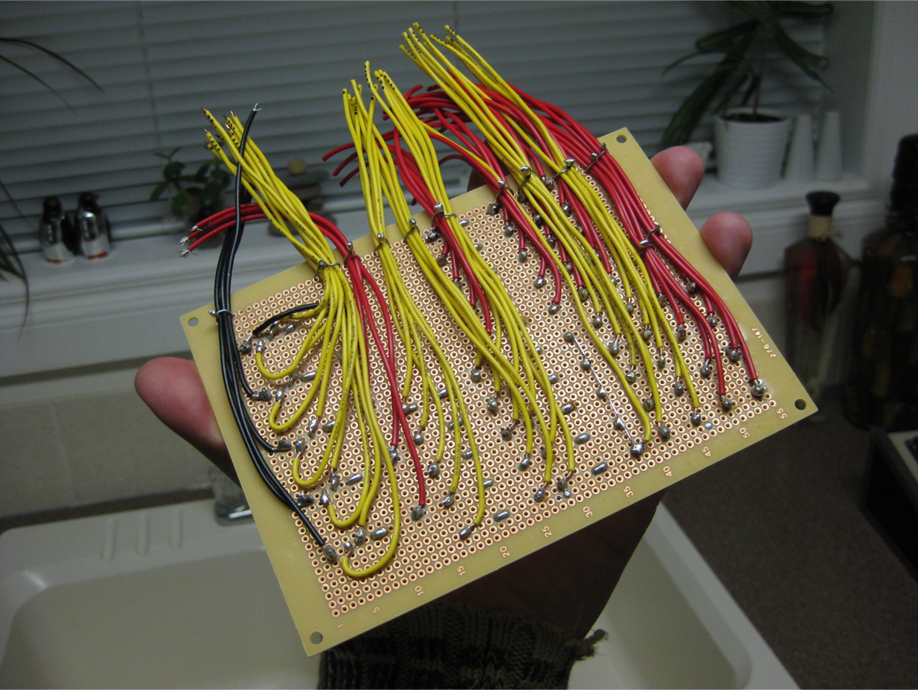 Blank PC board with soldered resistors and bridge rectifiers and wire leads protruding from one edge