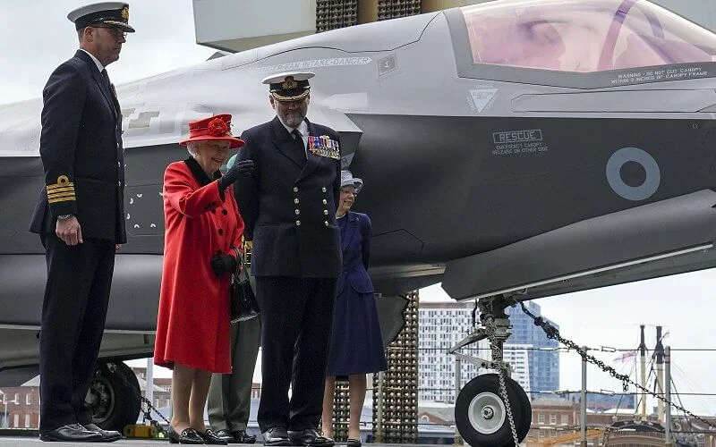 Queen Elizabeth wore a red coat, gold diamond brooch. HMS Queen Elizabeth and sister aircraft carrier HMS Prince of Wales