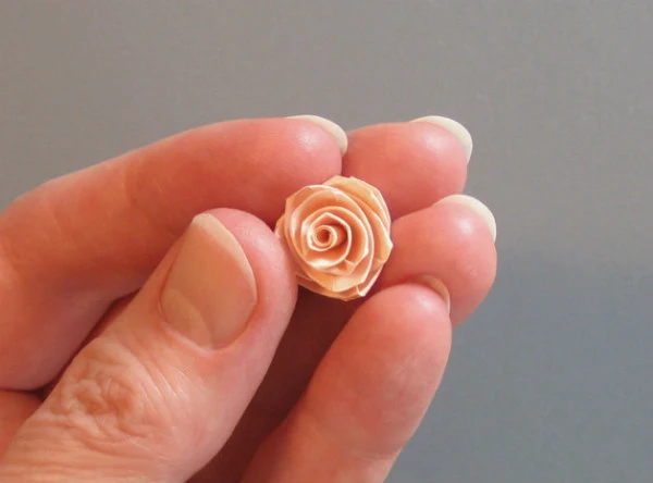 fingers holding a miniature folded paper rose