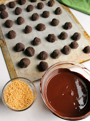 tray of frozen chocolate peanut butter oreo truffles with bowl of melted chocolate and bowl of chopped peanuts ready to assemble