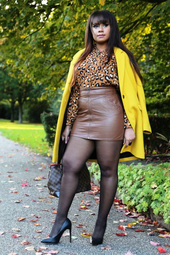 Plus size woman wearing a brown leather mini skirt, black tights and black pumps