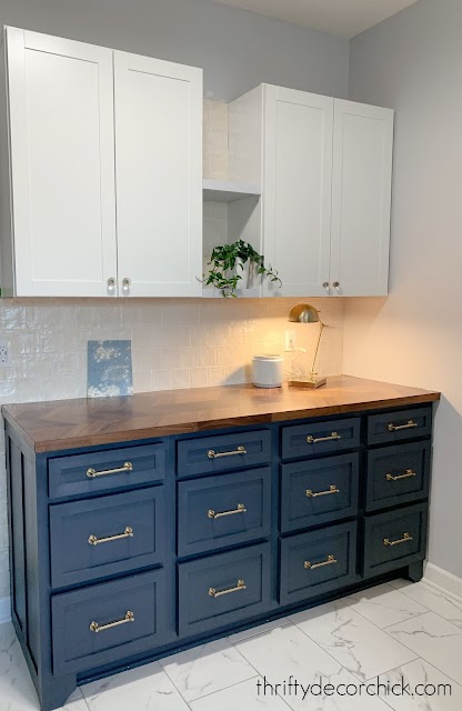 Dark blue cabinets, wood counter, cream shiny tile