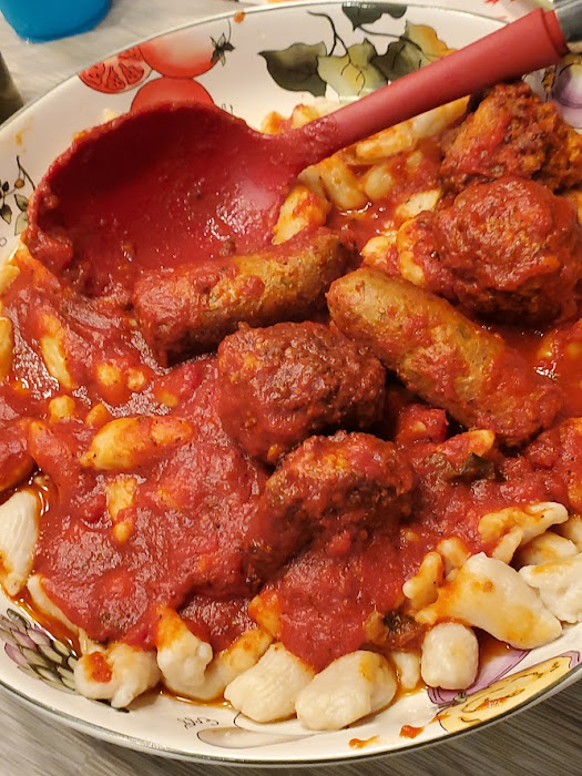 this is a big porcelain bowl with homemade potato gnocchi hand made topped with tomato  sauce and meats