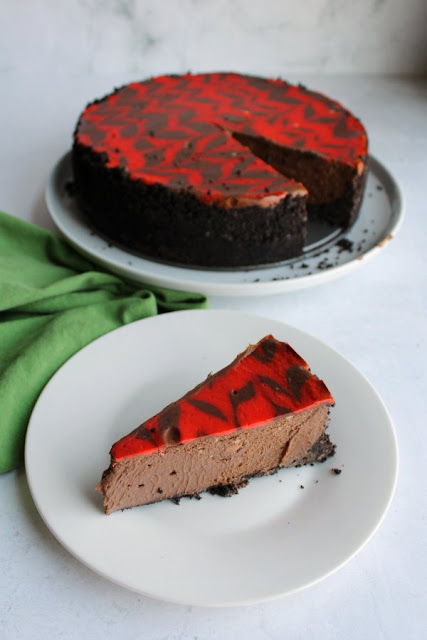 This no fail creamy chocolate cheesecake is rich and delicious. It is a perfect make ahead dessert for any occasion. slice of chocolate cheesecake served on small plate in front of remaining dessert