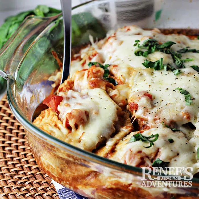 Baked Eggplant Parmesan in casserole dish, ready to serve, with serving spoon