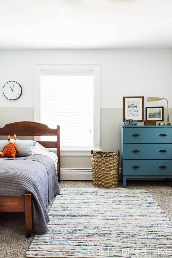 Boy's bedroom with antique bed, color blocked walls, denim rug, and blue dresser. 