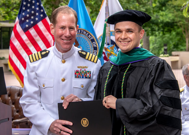 Dmitriy Treyster (right) receives his Doctor of Medicine diploma from Navy Capt. (Dr.) Eric Elster, interim dean of USU’s Hebert School of Medicine, during the University’s commencement ceremony, May 15. (Photo by Thomas Balfour, Uniformed Services University)